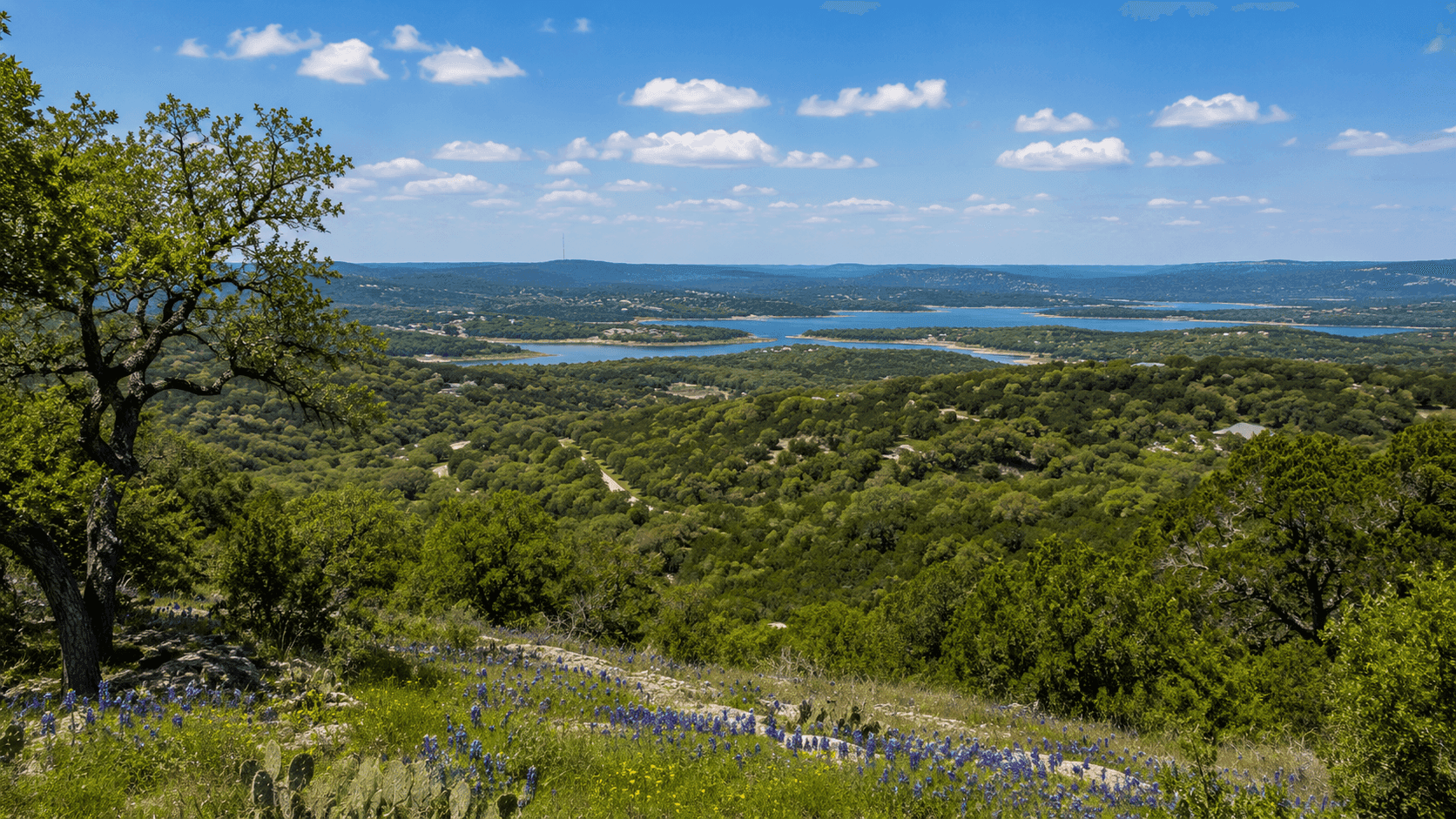 A panoramic view of the Texas Hill Country near Burnet, with rolling oak-covered hills and the Highland Lakes visible in the distance.