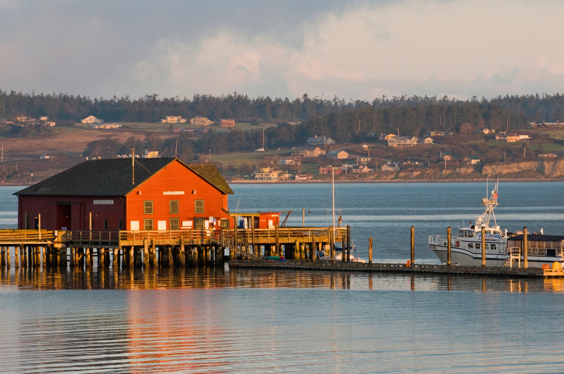 Scenic view of Coupeville, Washington on Whidbey Island, with calm water and evergreen trees under Pacific Northwest skies.