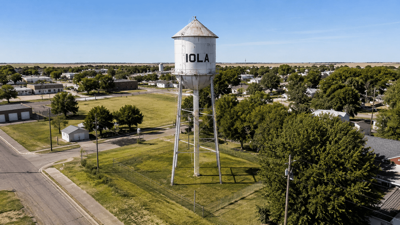 A historic water tower on a flat open lot in Iola, Kansas