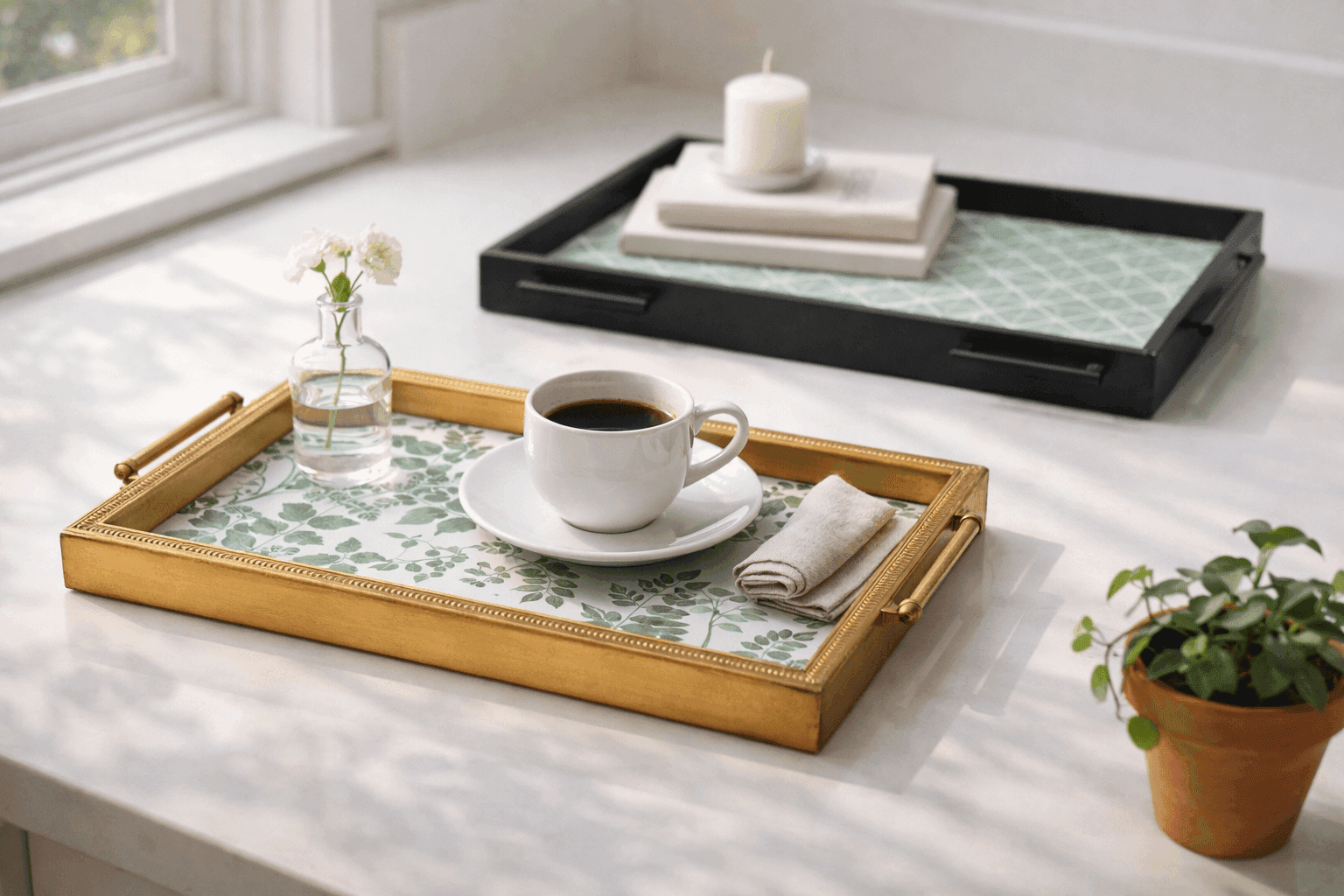 Two completed picture frame serving trays with decorative paper inserts and brass drawer pull handles displayed on a kitchen counter with styled coffee cups and small plants